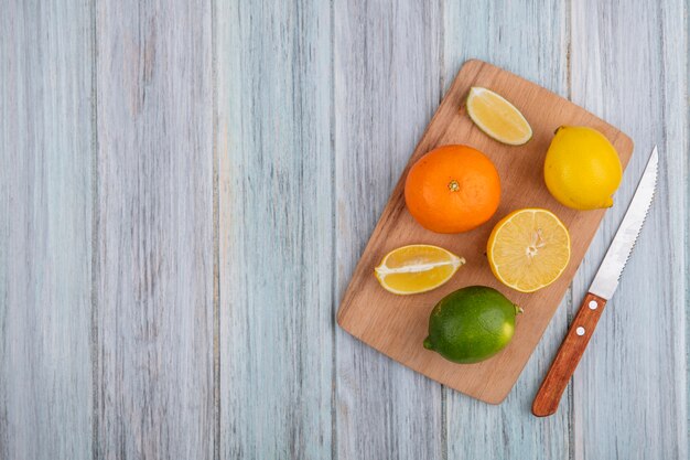 Espacio de copia de vista superior naranja con limón y lima en tabla de cortar con cuchillo sobre fondo gris