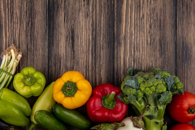 Espacio de copia de vista superior pepinos con pimientos de colores brócoli y tomates sobre fondo de madera