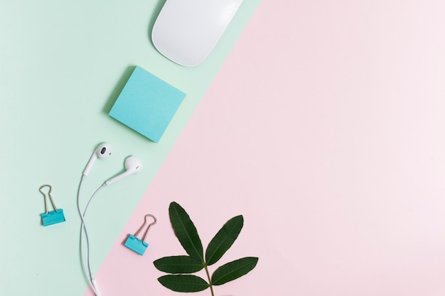 Espacio de trabajo con auriculares y ratón sobre fondo rosa y verde