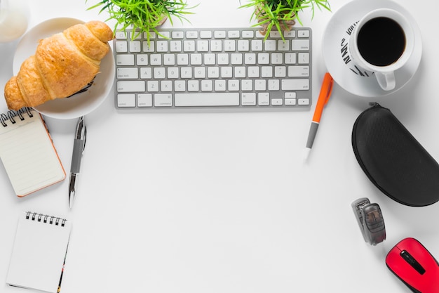 Foto gratuita espacio de trabajo blanco con papelería de oficina y desayuno.