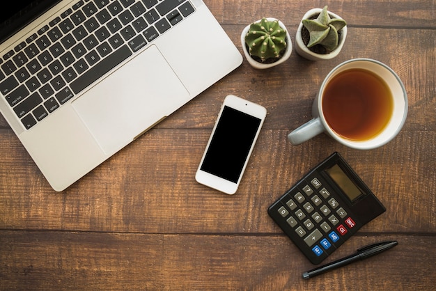 Espacio de trabajo con computadora portátil y teléfono inteligente cerca de la taza de té