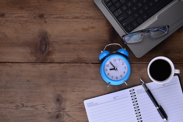 Foto gratuita espacio de trabajo con libreta reloj café y portátil