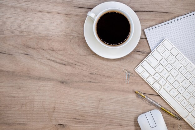 Espacio de trabajo con material de oficina y taza de café.