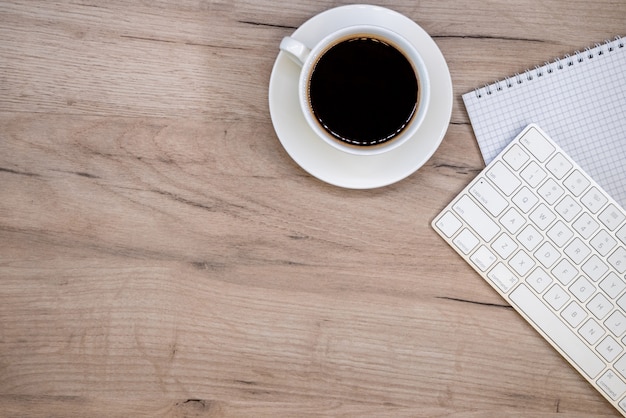 Espacio de trabajo con material de oficina y taza de café.