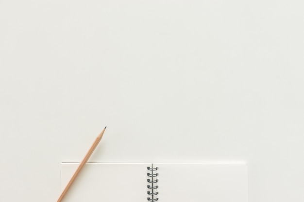 Espacio de trabajo mínimo - foto plana estable creativa de escritorio de espacio de trabajo con cuaderno de dibujo y lápiz de madera sobre fondo blanco de espacio de copia. Vista superior, fotografía plana.