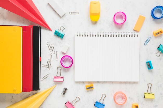 Espacio de trabajo que consta de cuaderno en blanco y suministros de oficina a su alrededor