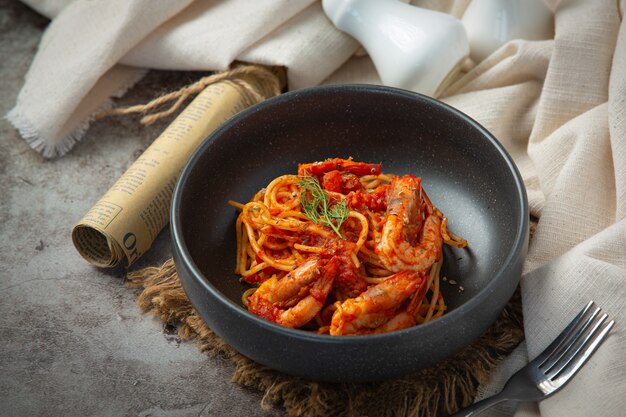 Espaguetis con camarones en salsa de tomate sobre fondo oscuro