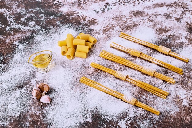 Espaguetis crudos crudos y macarrones en la mesa de la cocina de madera.