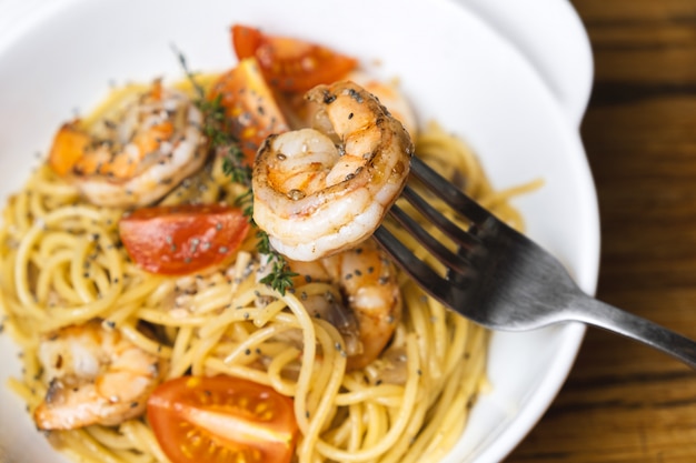 Espaguetis con gambas fritas y tomates frescos.