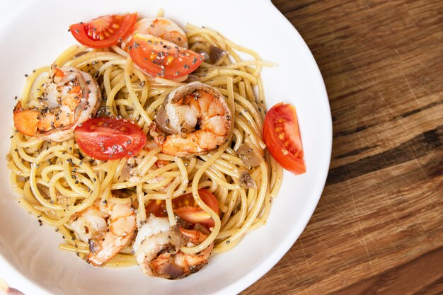 Espaguetis con gambas fritas y tomates frescos.