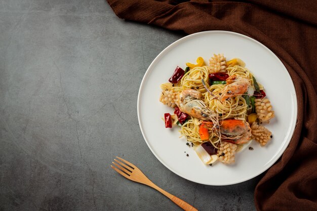 Espaguetis con mariscos mixtos picantes sobre fondo oscuro