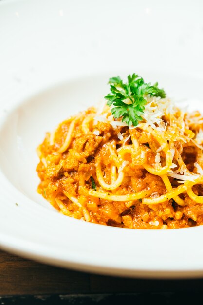 Espaguetis o pasta boloñesa en plato blanco.