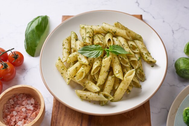 Espaguetis de pasta con calabacín, albahaca, crema y queso sobre mesa de piedra negra.