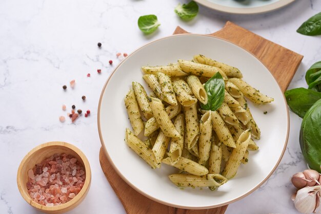 Espaguetis de pasta con calabacín, albahaca, crema y queso sobre mesa de piedra.