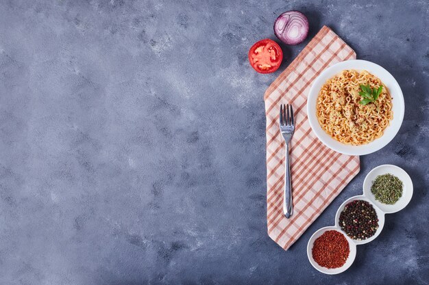 Espaguetis en un plato blanco con especias alrededor.