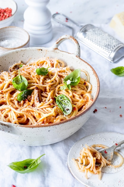 Espaguetis con salsa de tomate marinara cubiertos con parmesano y albahaca fotografía de alimentos