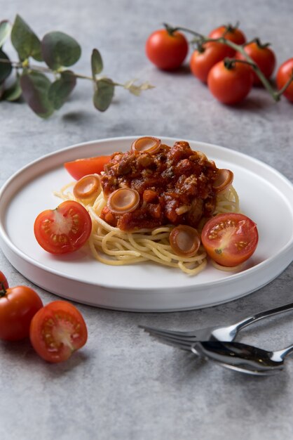 Espaguetis con salsa de tomate y salchichas en plato blanco