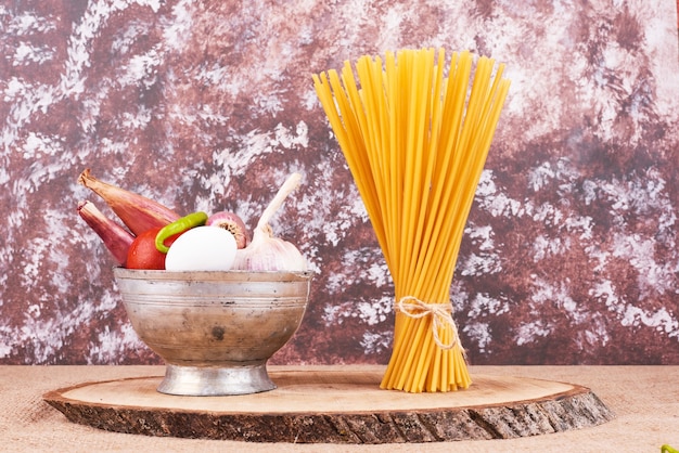 Espaguetis en una tabla de madera con ingredientes.