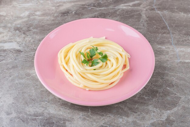 Espaguetis y verduras en el plato, en el mármol.