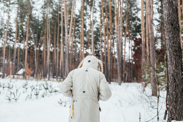 La espalda del hombre en abrigo de invierno camina hacia el bosque nevado