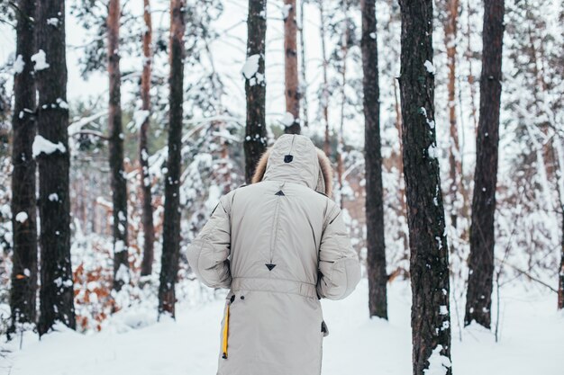 La espalda del hombre en abrigo de invierno camina hacia el bosque nevado