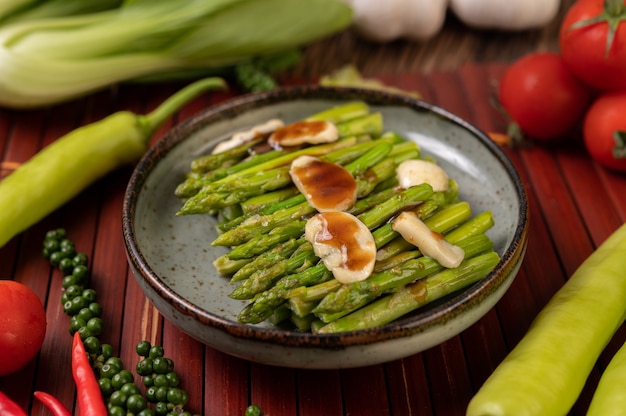 Espárragos fritos con salsa de ostras en un plato con pimientos