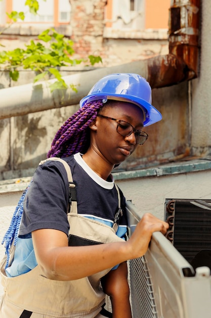 Foto gratuita especialista afroamericano en el ensamblaje de aire acondicionado después de terminar de reacondicionar componentes oxidados ingeniero con licencia comisionado por el cliente para hacer el mantenimiento del sistema hvac