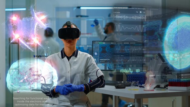 Especialista científico en laboratorio de investigación que usa gafas de realidad virtual utilizando equipos de alta tecnología y sensores cableados para hacer estudios médicos. Médico que utiliza tecnología de realidad virtual para visualizar conjuntos de datos