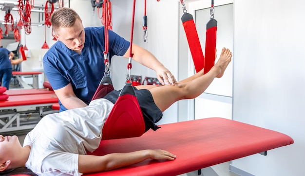 Foto gratuita especialista en rehabilitación realizando tratamiento con correas de suspensión al paciente