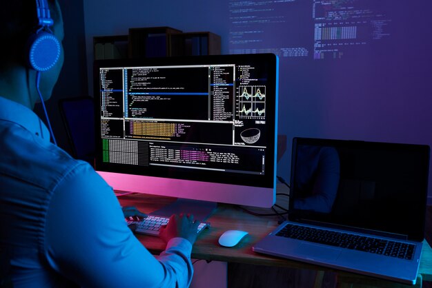 Especialista en TI revisando el código en la computadora en la oscura oficina por la noche