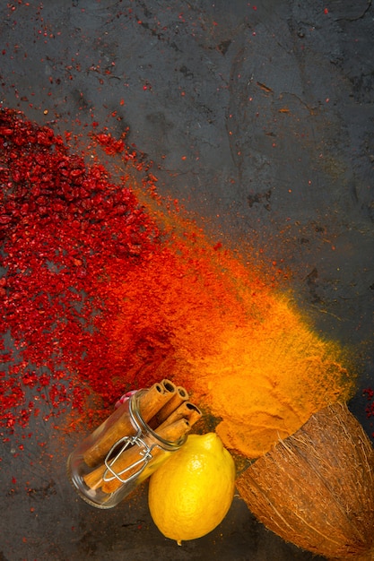 especias de colores superiores con palitos de canela limón y coco sobre negro