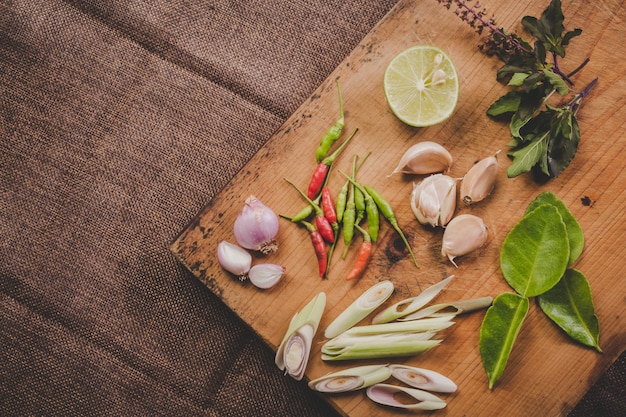 Especias Tom Yum que se colocan en una tabla de cortar de madera marrón y tienen una madera de color marrón oscuro.