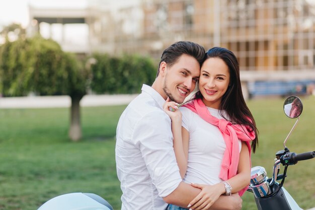 Espectacular mujer en brazalete de plata acariciando suavemente a su marido, posando con él en la plaza