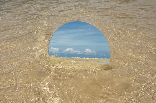 Espejo de cristal redondo en la playa que refleja el paisaje