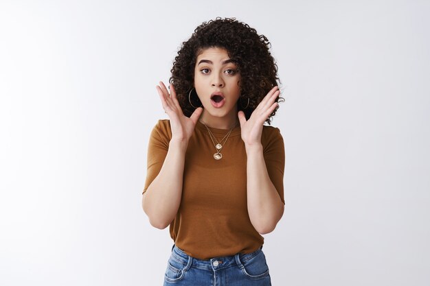 Espera, mira qué. Conmocionado impresionado sin palabras joven guapa recibir una promoción inesperada mirada sorprendida mandíbula caída agitando las manos preocupado emocionado de pie aturdido asombrado fondo blanco