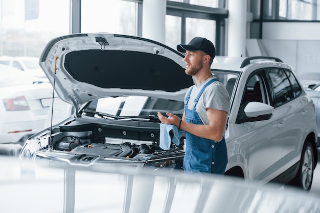 Esperando al cliente. Empleado en el uniforme de color azul se encuentra en el salón del automóvil