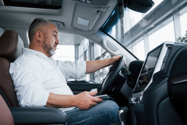 Esperando una llamada. El hombre de negocios se sienta en el automóvil moderno y tiene algunas ofertas