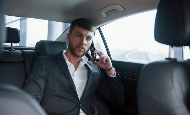 Esperando la respuesta. Hombre de negocios en ropa oficial tiene llamada cuando está sentado en la parte trasera del coche