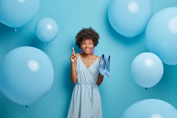 Foto gratuito esperanza joven afroamericana cruza los dedos, pide un deseo, usa zapatos de tacón alto y vestido, vestidos para la fiesta, se encuentra en el interior