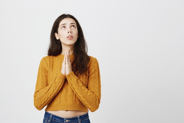 Foto gratuita esperanza preocupada chica cogidos de la mano en súplica y buscando milagro en la esquina superior derecha, suplicando