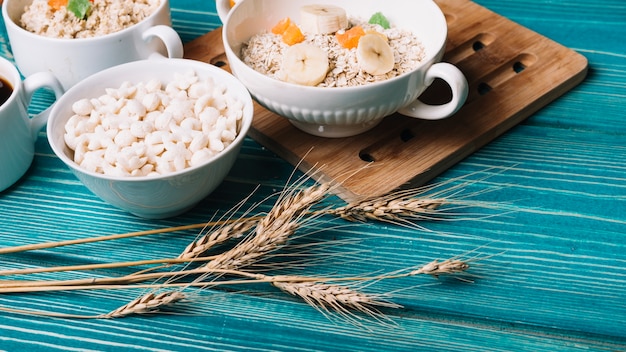 Espiga de trigo con tazón de avena y cereales en la mesa de madera