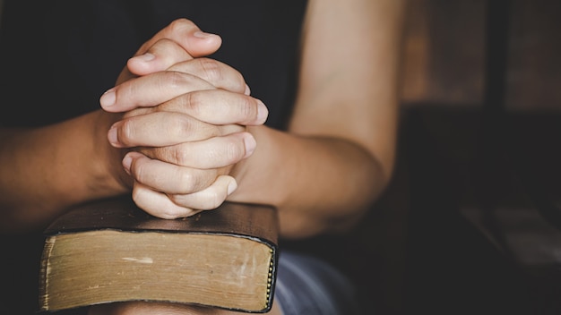 Espiritualidad y religión, las manos juntas en oración en una Santa Biblia en la iglesia