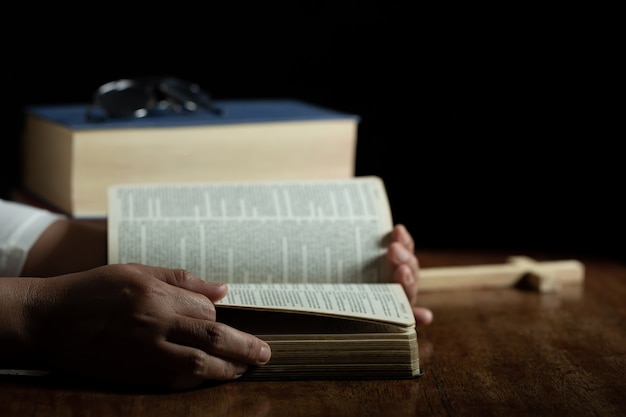 Espiritualidad y religión, manos juntas en oración sobre una Santa Biblia en la iglesia