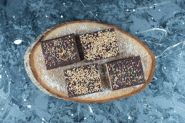 Espolvorear azúcar sobre un gofre de chocolate sobre una tabla, sobre la mesa azul.