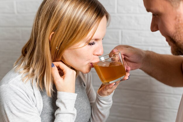 Esposa embarazada bebiendo té ayudada por su esposo