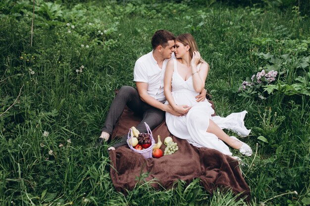 La esposa y el esposo sentados en el plaid con frutas