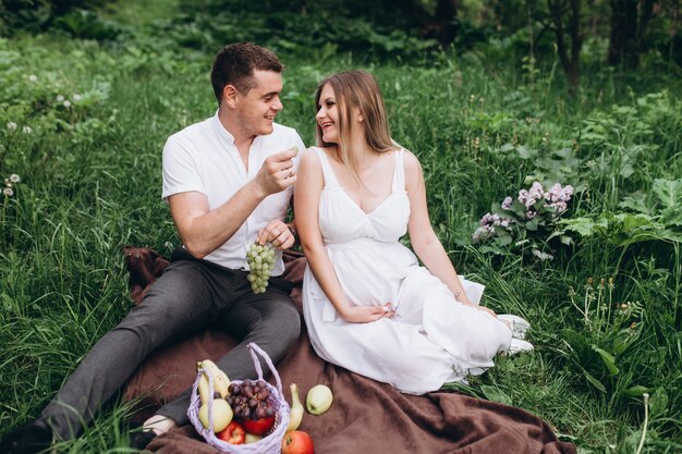 La esposa y el esposo sentados en el plaid con frutas