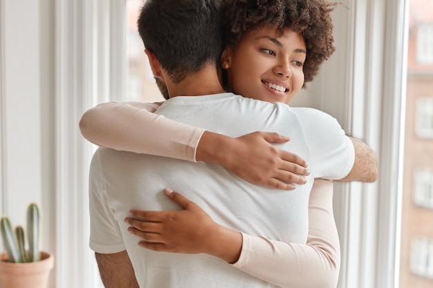 Esposa de piel oscura positiva abraza a su marido