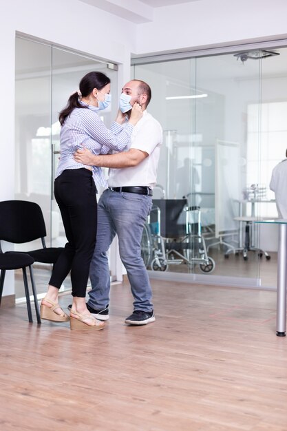 Esposo abrazando a la esposa después de recibir buenas noticias del médico en la sala de espera del hospital