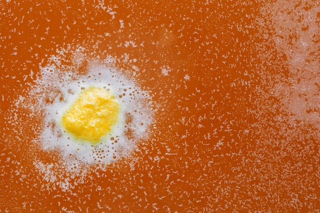 Espuma amarilla y blanca sobre agua naranja